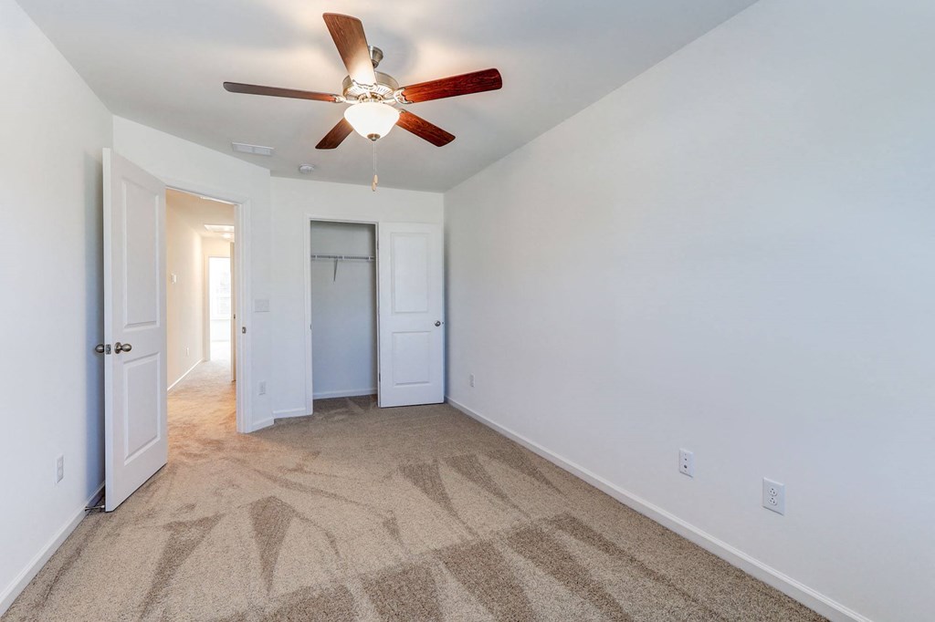 a living room with carpet and a ceiling fan