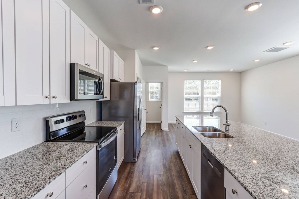 North Charleston, SC Townhomes Near Tanger Outlets - Highland Townhomes - Kitchen with Hardwood Floor, Stainless Steel Appliances, Granite Countertops, and White Cabinetry.