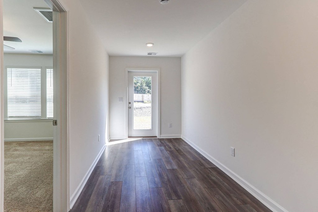 a living room with white walls and wood flooring and a door