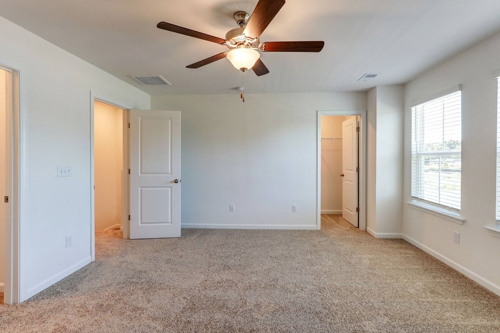 an empty living room with a ceiling fan and window