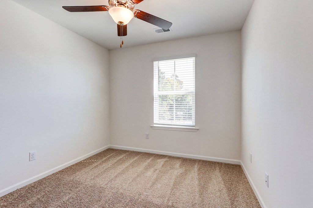 an empty room with a ceiling fan and a window