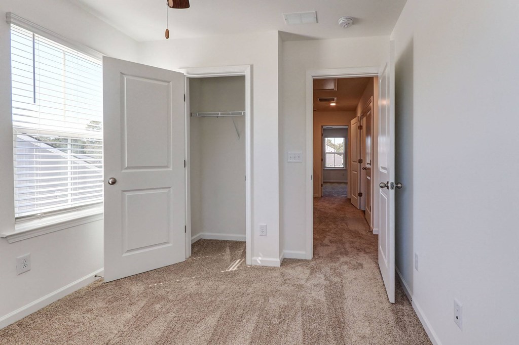 4-BR Townhomes in North Charleston, SC - Highland Townhomes - Empty Bedroom With Carpet Flooring, A Large Window, White Walls, and A Closet
