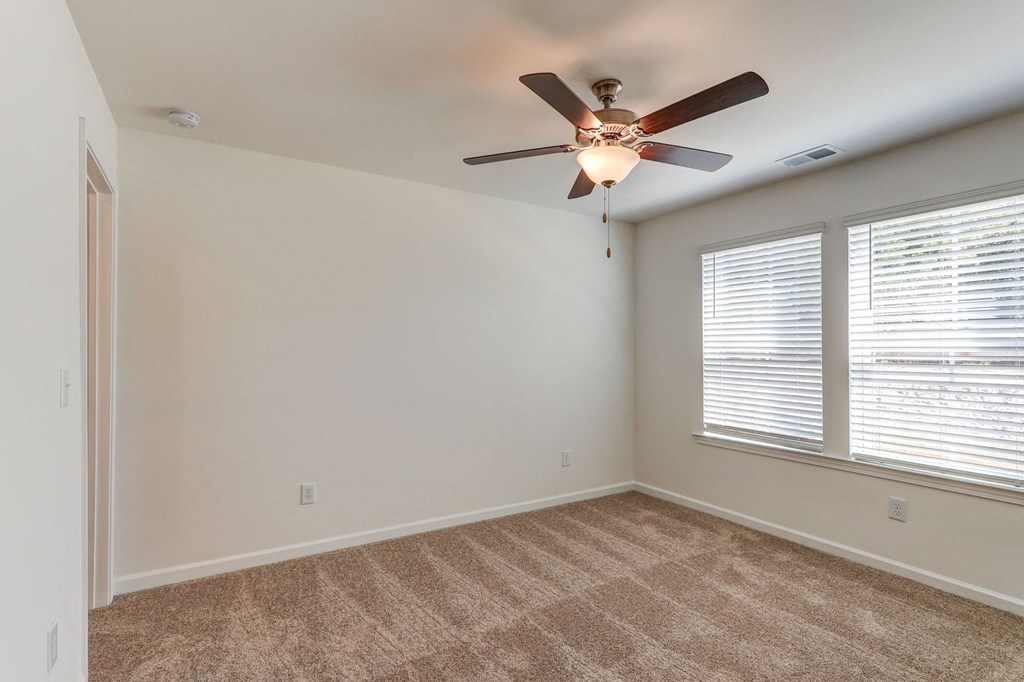 an empty room with a ceiling fan and a window