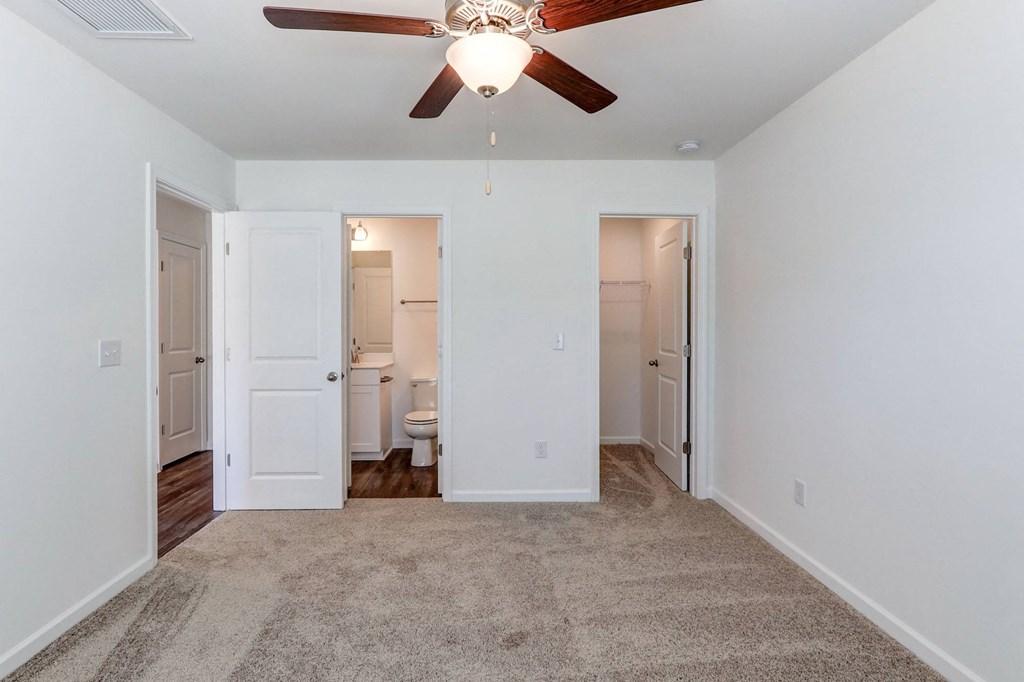Townhouses For Rent In North Charleston, SC - Highland Townhomes - Spacious Bedroom With Plush Carpeting, Ceiling Fan, Walk-In Closet, And Bathroom