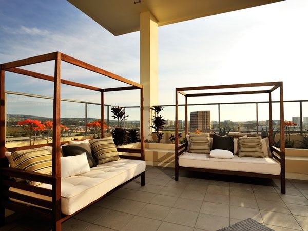 Two wooden daybeds with cushions and pillows on a patio.