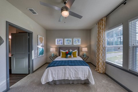 Spacious primary bedroom with ceiling fan and large windows in luxury Jacksonville apartments near UNF.