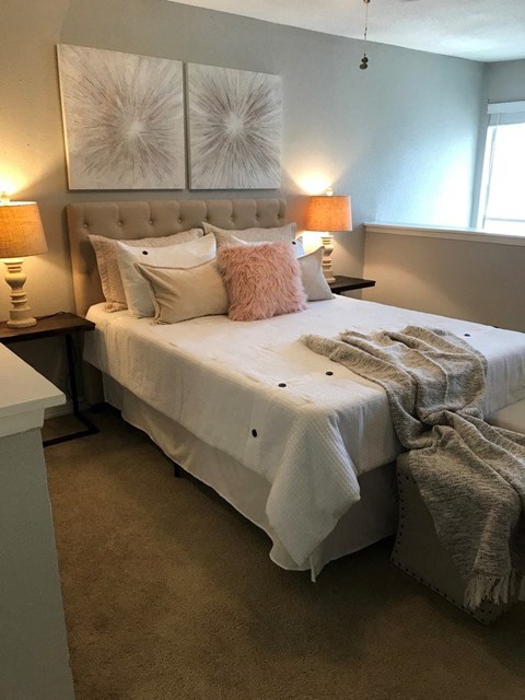 A bedroom with a large bed and two lamps on either side.