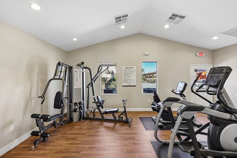 A gym with a variety of equipment including treadmills, weights, and exercise machines.