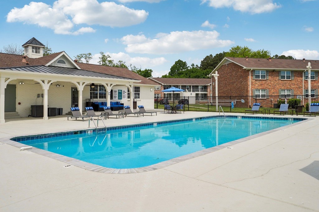 Apartment complex swimming pool with lounge chairs and clubhouse.