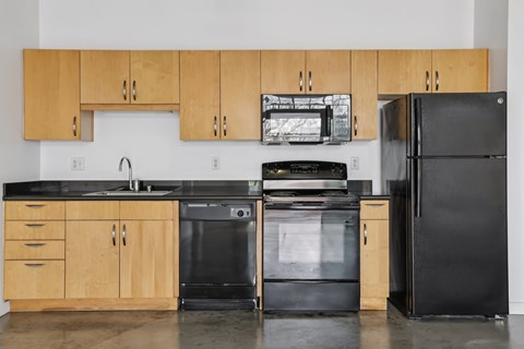A kitchen with black appliances and wooden cabinets.