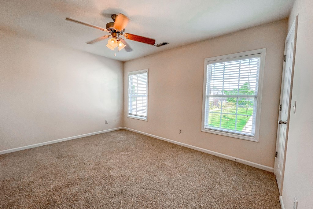 an empty bedroom with a ceiling fan and a window
