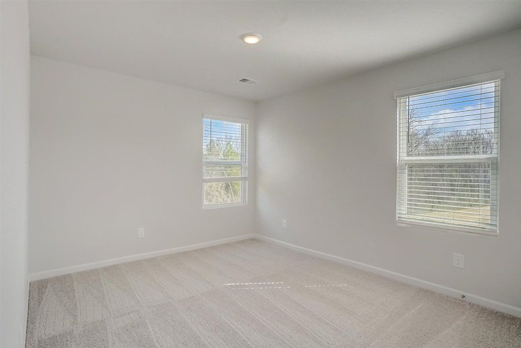 A room with two windows and a carpeted floor.