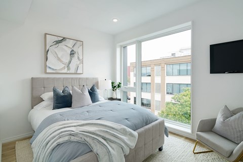 A bedroom with a large bed and a chair.