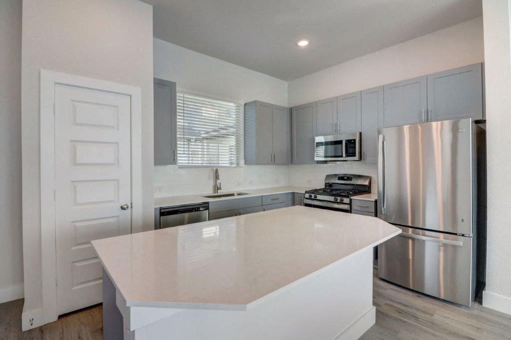 a white kitchen with stainless steel appliances and a white island
