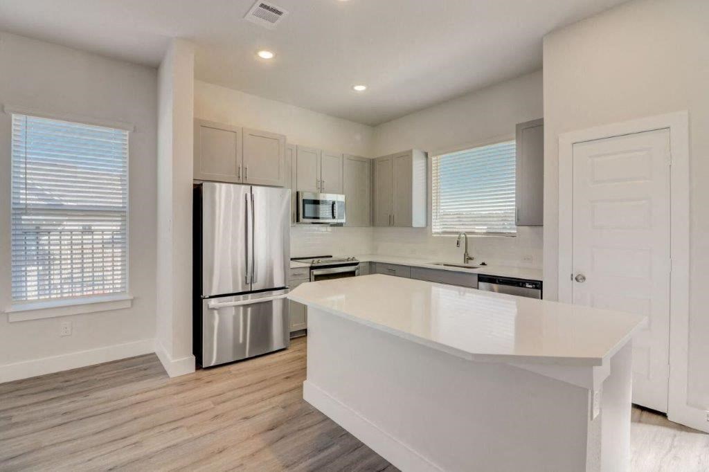 a kitchen with a white counter top and a stainless steel refrigerator