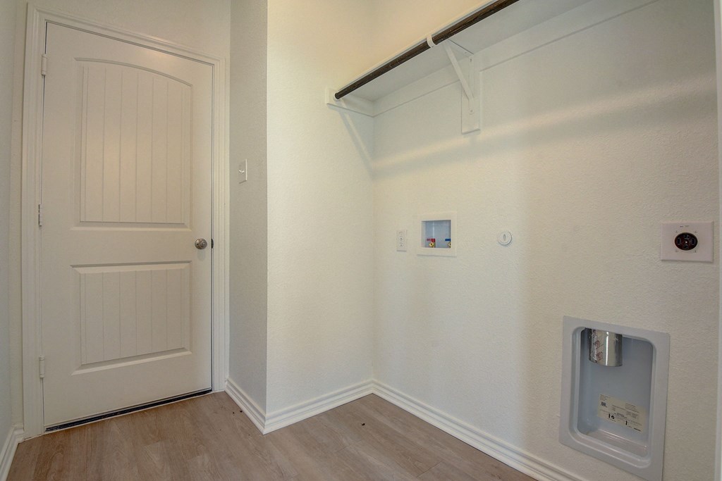 an empty room with a white door and a washing machine on the wall