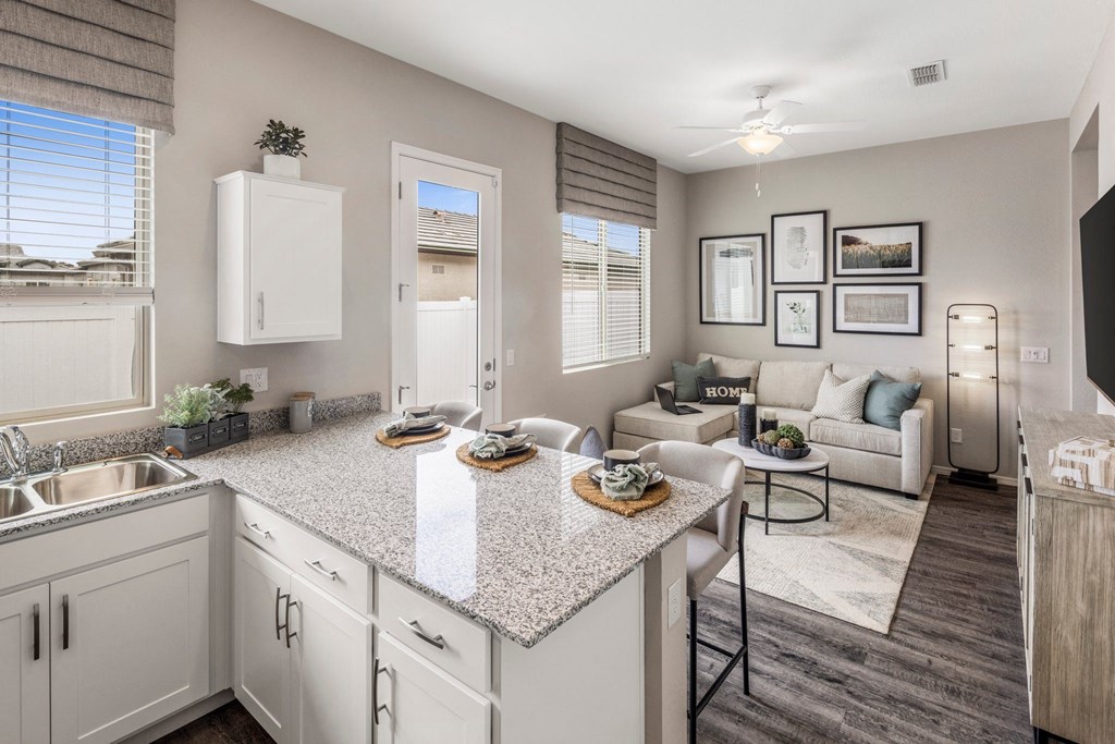 A kitchen with a granite countertop and a dining area with a white couch.