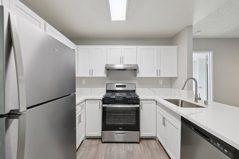 A modern kitchen with a stainless steel refrigerator and white cabinets.