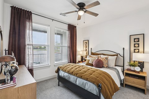 A bedroom with a bed, nightstand, and window with curtains.