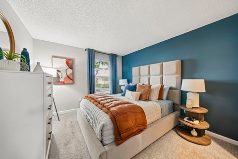 A bedroom with a large bed and a white dresser.