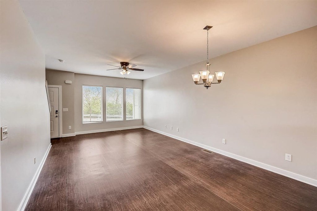 an empty living room with a ceiling fan and chandelier