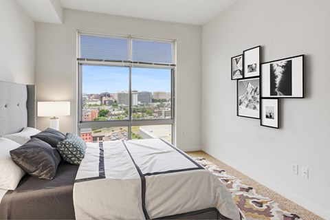 a bedroom with a bed and a window with a city view
