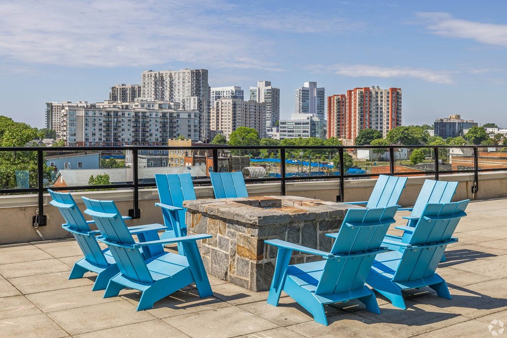a deck with blue chairs and a fire pit with a view of the city
