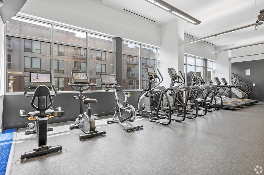 a gym with cardio equipment and windows in a building