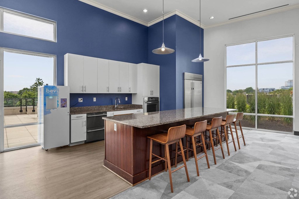 a kitchen with a counter and chairs in front of a large window