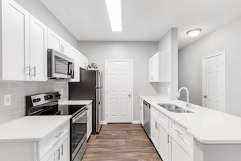 a white kitchen with white cabinets and black appliances