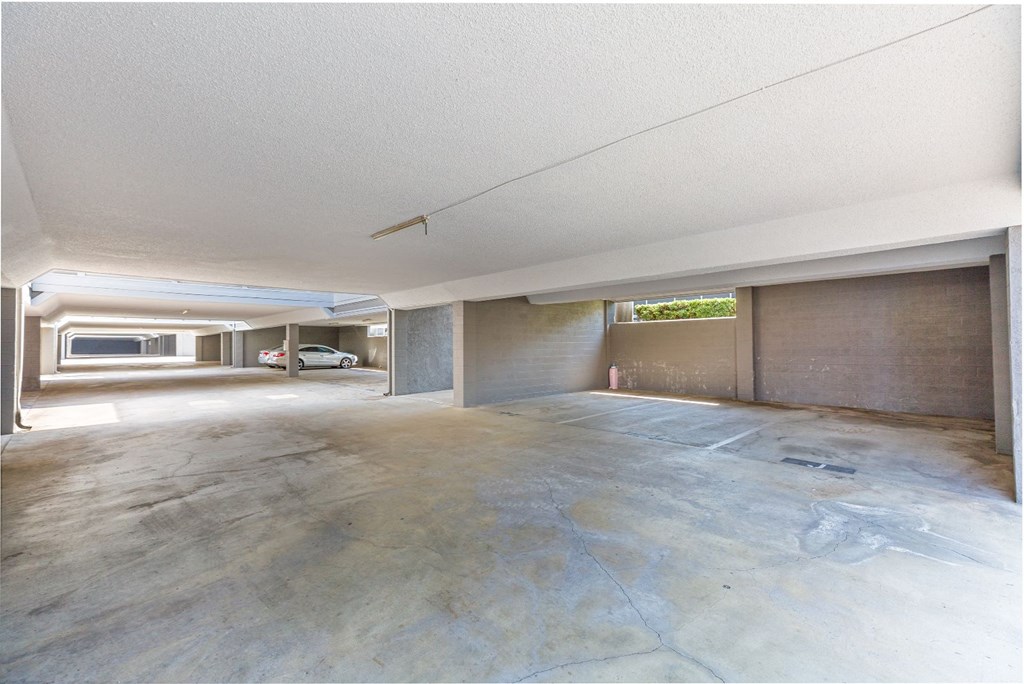 an empty garage with a concrete floor and a car parked in the distance