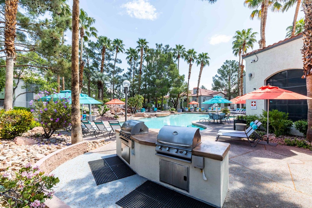 a patio with a grill and a swimming pool with umbrellas