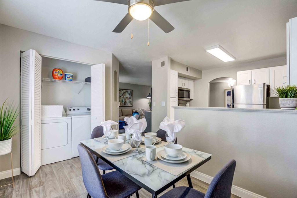 a dining room table and a kitchen with a ceiling fan