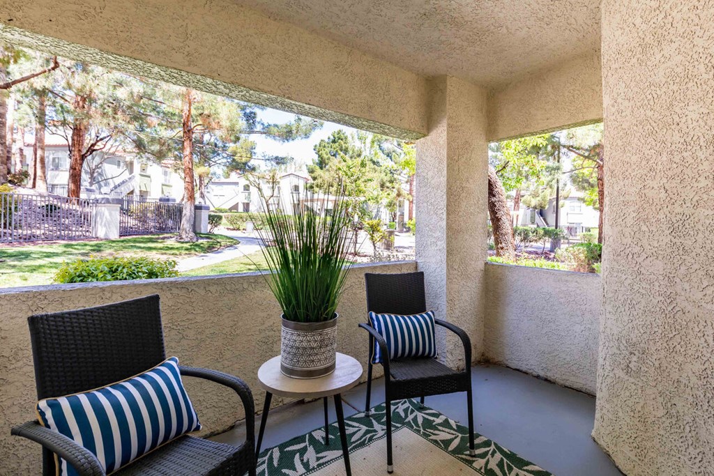 a patio with chairs and a table with a plant on it
