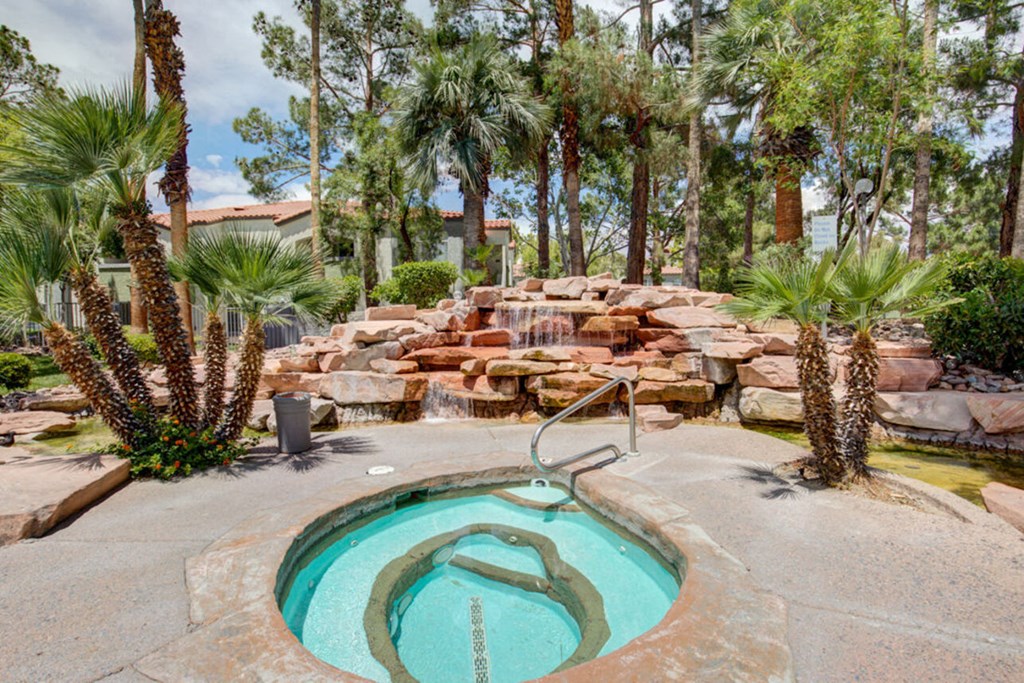a spa with a rock waterfall and a pool with palm trees