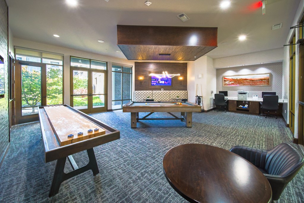 Modern recreation room with pool table, shuffleboard, computer workstations, and lounge seating.