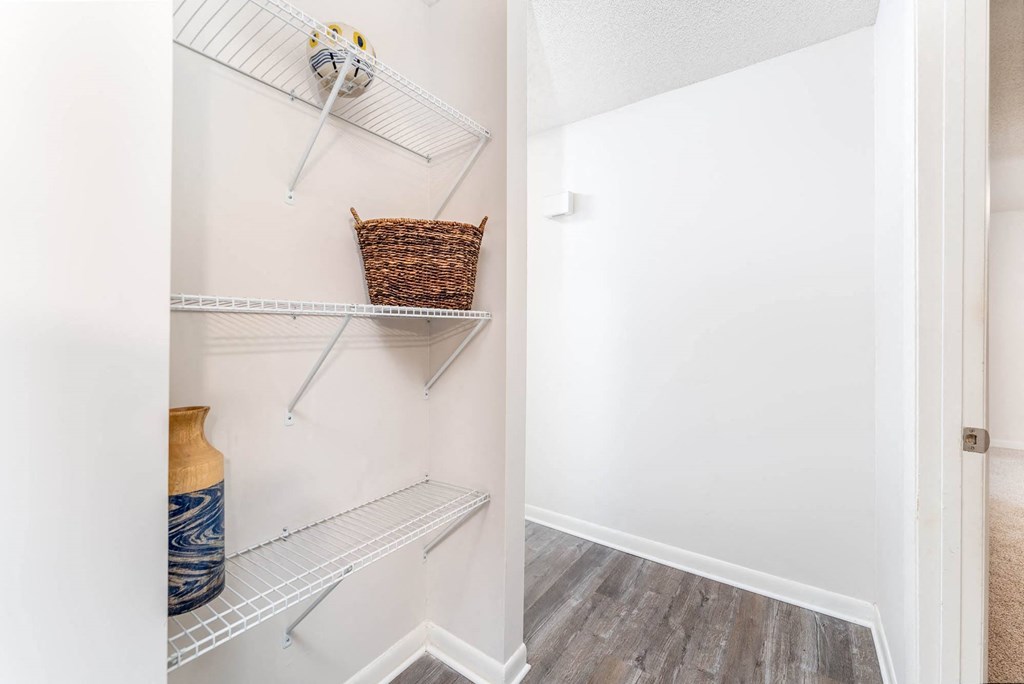 a walk in closet with shelves and a basket on the wall