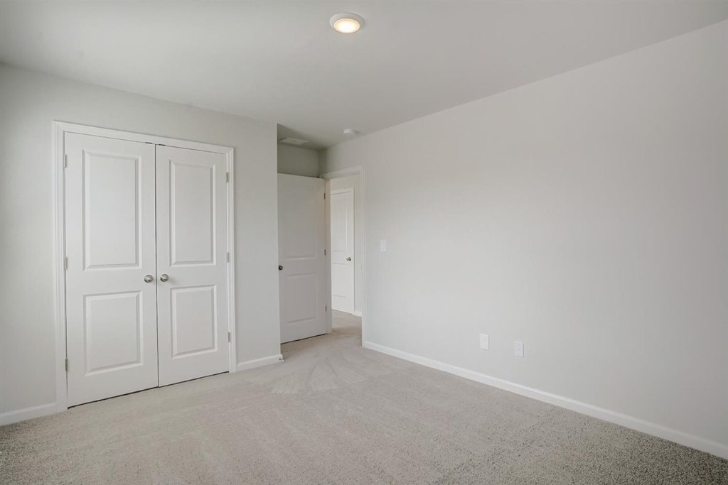 A room with a white door and carpeted floor.