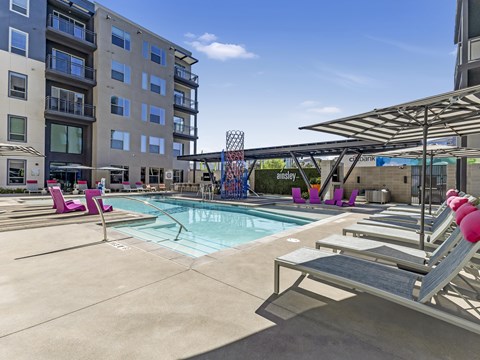 A pool area with lounge chairs and a building in the background.