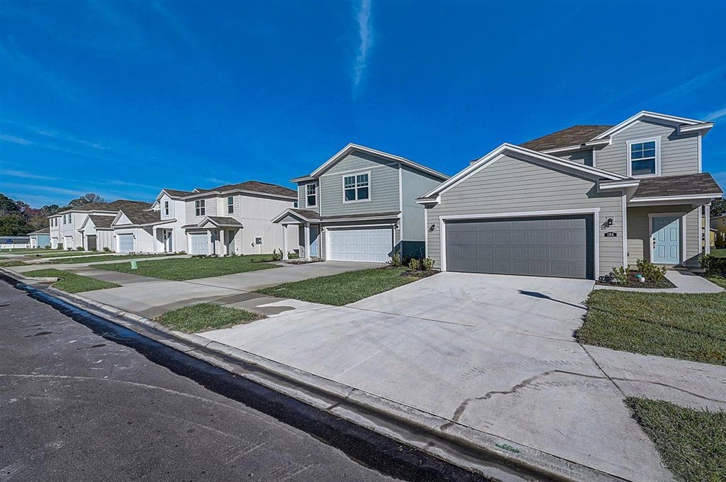 Row of new, two-story single-family homes with attached garages on a sunny day.