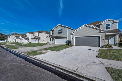 Row of new, two-story single-family homes with attached garages on a sunny day.