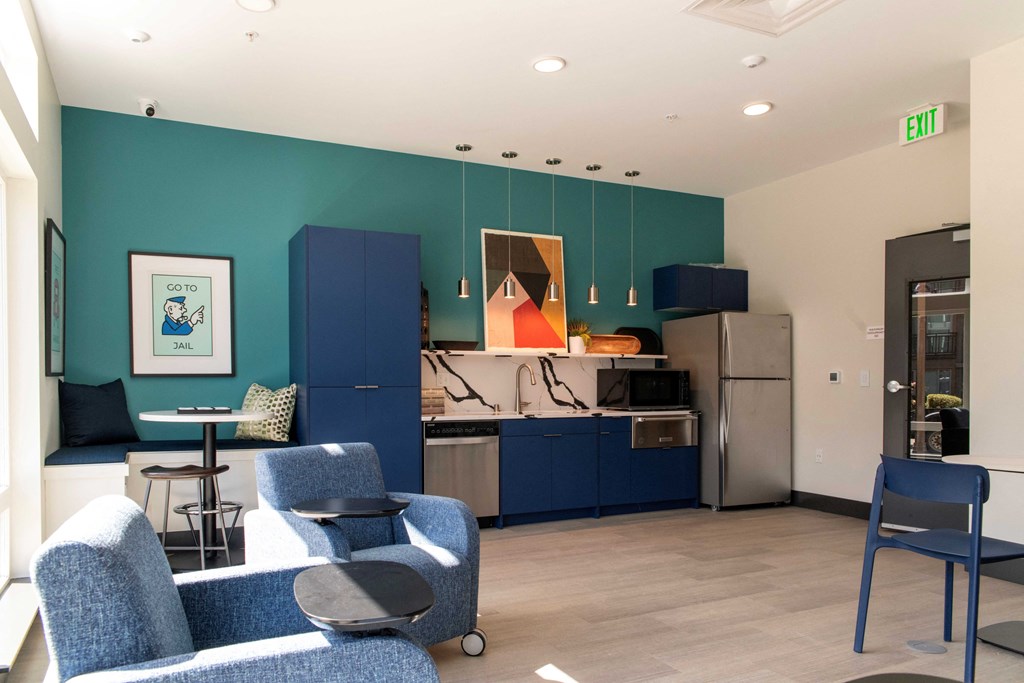 1-Bedroom Apartments in Bothell, WA - Morado Bothell - Community Kitchen with Blue Cabinetry, Stainless Steel Appliances, Marble Backsplash, Various Seating Options, and Stylish Decor