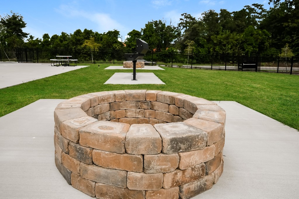 A stone fire pit sits in the middle of a concrete patio.