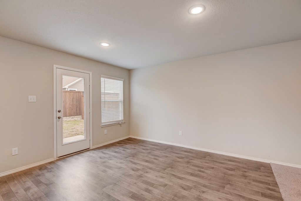 an empty living room with white walls and a door to a patio
