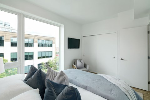 A bedroom with a large bed and a flat screen TV mounted on the wall.