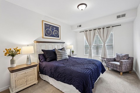 A bedroom with a bed, chair, and a picture of a bicycle on the wall.