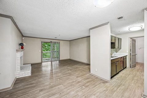 A spacious room with light wood flooring and white walls.