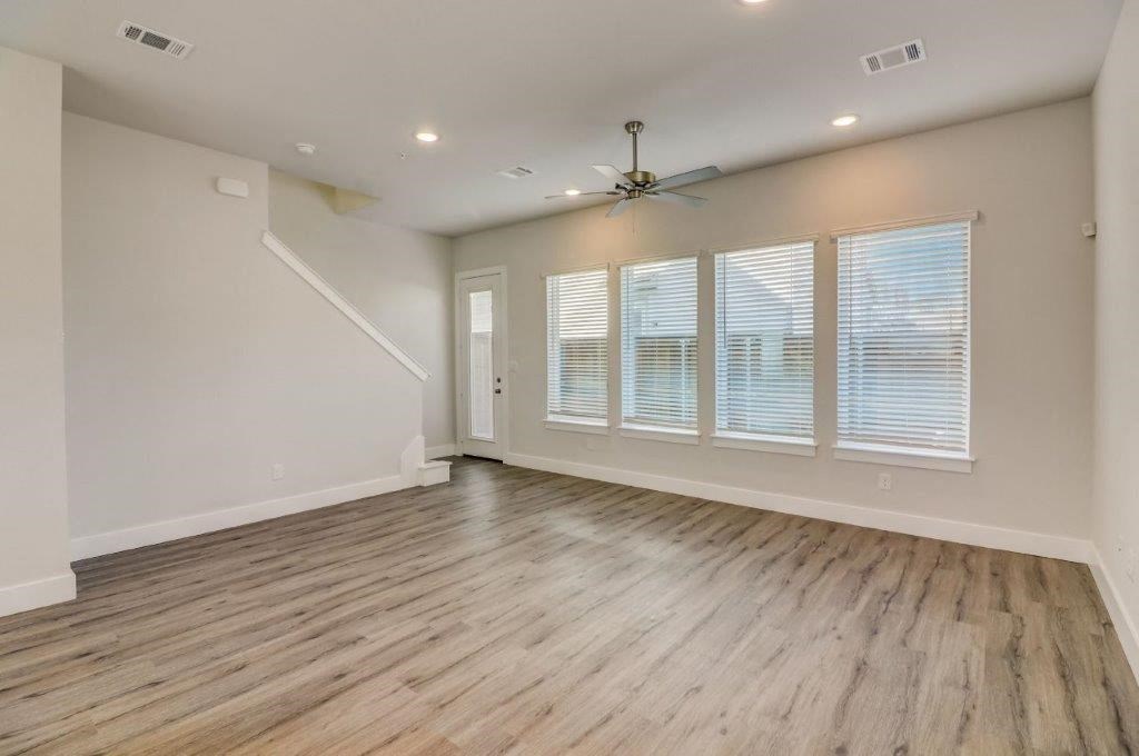 an empty living room with wood floors and a ceiling fan