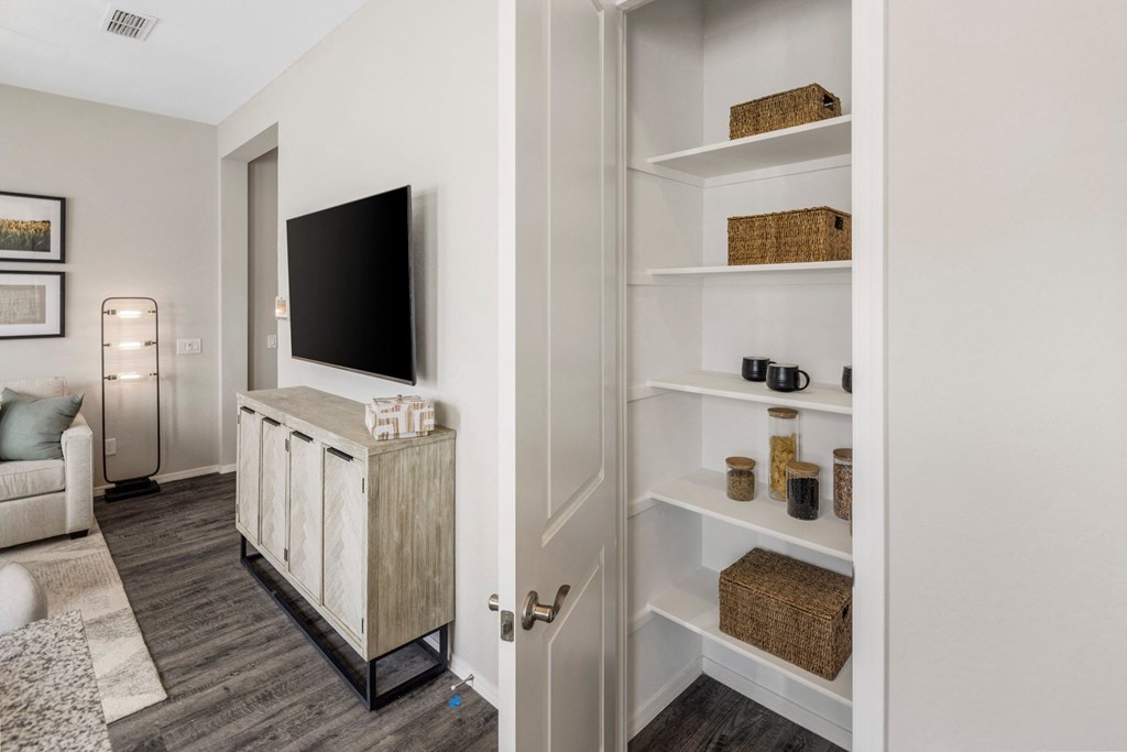 A white shelving unit with various decorative items sits in a room with a white couch and a television.