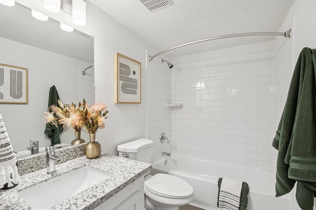 Studio Apartments in North Mountain Village, Phoenix, AZ - Ardella on 28th - Bathroom with Wood-Style Flooring, Granite Counter Sink with White Cabinetry, Mirror, and White Tile-Lined Shower with Tub.